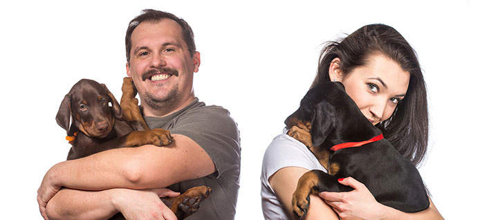 Two people holding their dogs against a white background.