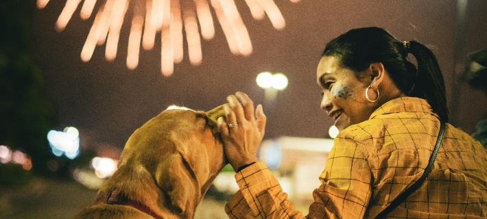 A woman petting her dog while watching fireworks