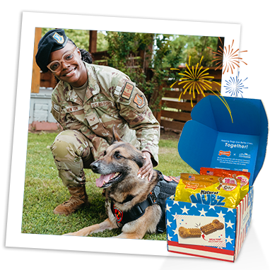 U.S. service member kneeling with a military dog beside Nubz red, white and blue box. U.S. service member kneeling with a military dog beside Nubz red, white and blue box.